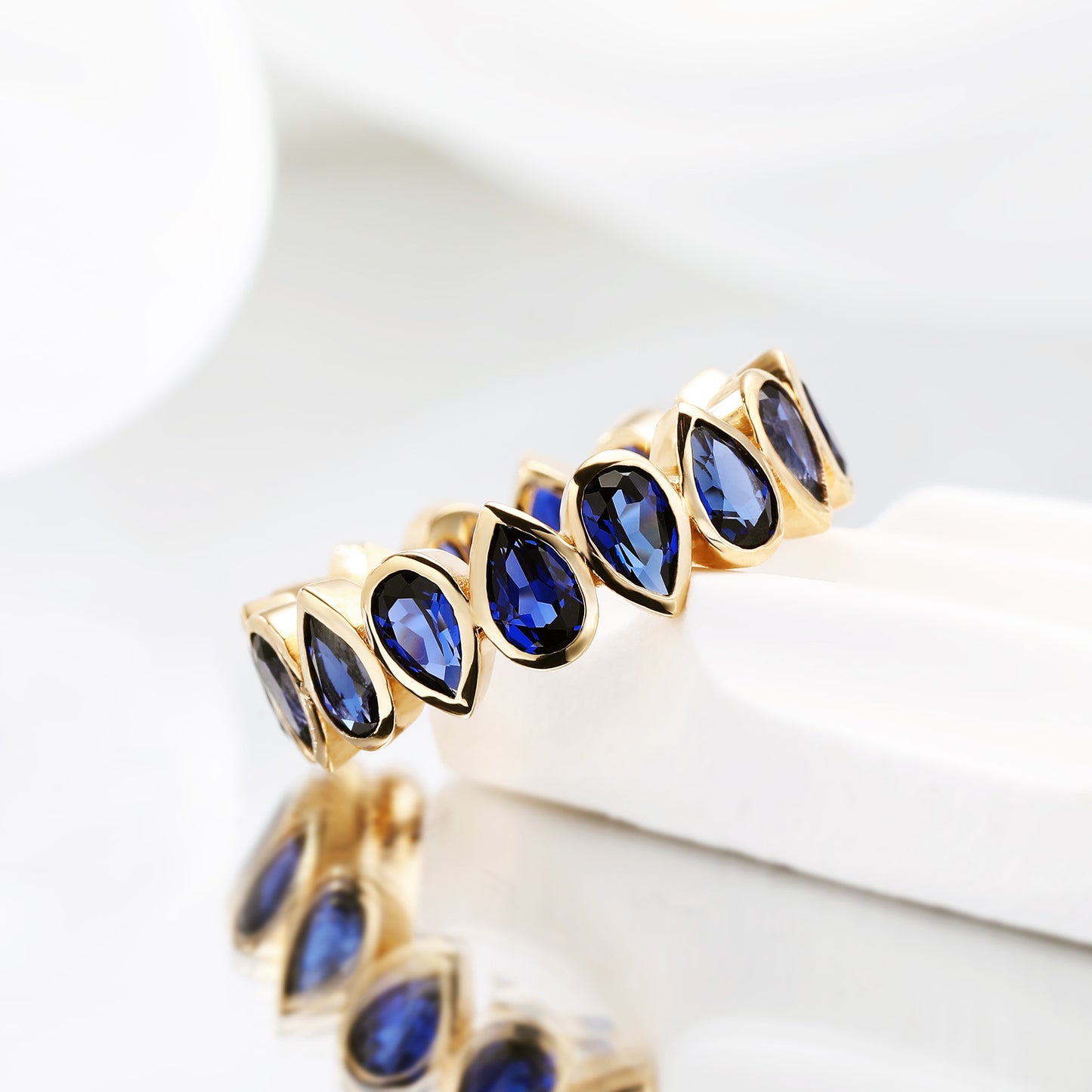 Bezel set Lab Grown Sapphire Royal Blue 3x5 pear shaped eternity band ring in gold